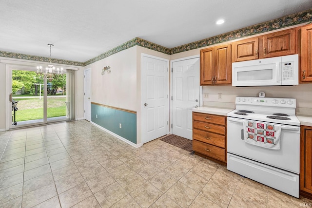 kitchen featuring white appliances, a chandelier, baseboards, and light countertops