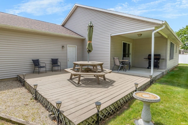 wooden deck featuring outdoor dining area, a grill, and a yard
