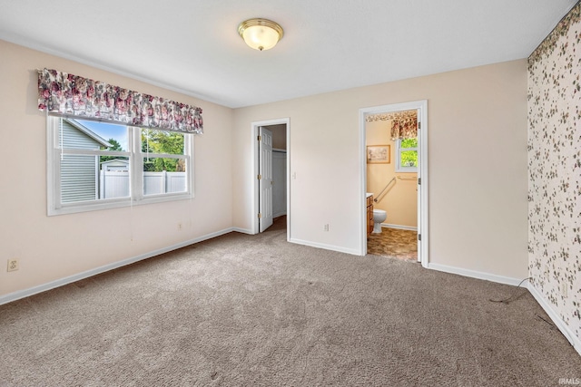 unfurnished bedroom with multiple windows, carpet flooring, baseboards, and wallpapered walls