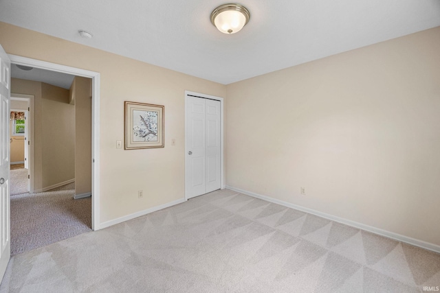 unfurnished bedroom featuring light carpet, baseboards, and a closet