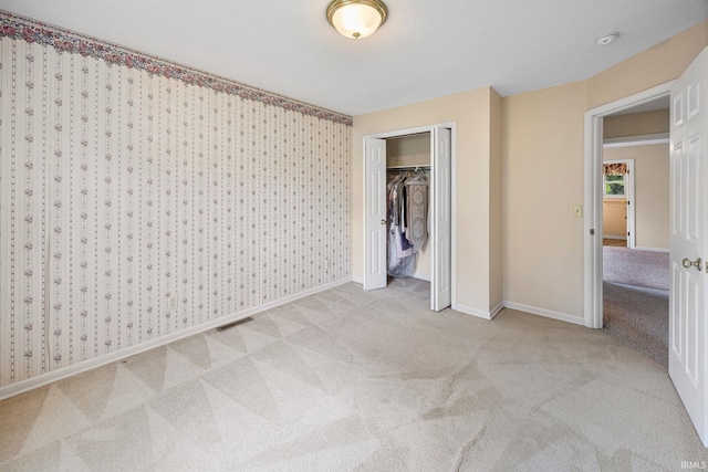 unfurnished bedroom featuring carpet floors, baseboards, and a closet