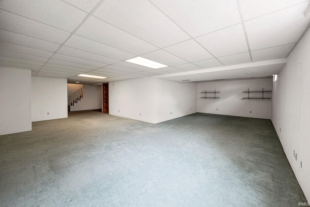 finished below grade area featuring stairs, a drop ceiling, and carpet flooring