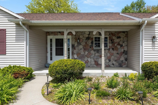 doorway to property with covered porch and roof with shingles