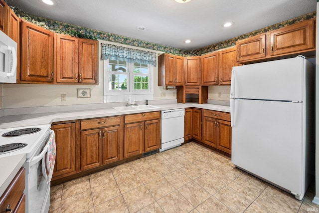 kitchen featuring white appliances, a sink, brown cabinets, light countertops, and recessed lighting