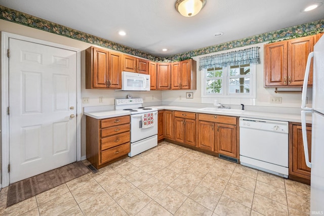 kitchen with white appliances, a sink, light countertops, brown cabinets, and recessed lighting