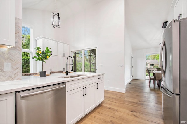 16166 Candlewycke Ct, Granger, IN 46530 - kitchen featuring appliances with stainless steel finishes, a sink, a towering ceiling, white cabinets, and light wood-style flooring