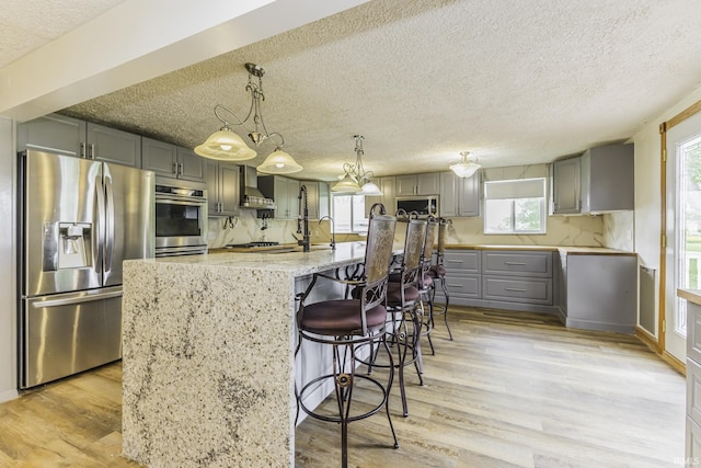 11009 S County Road 300 W, Muncie, IN 47302 - kitchen featuring appliances with stainless steel finishes, gray cabinetry, a textured ceiling, light wood-style flooring, and light stone countertops
