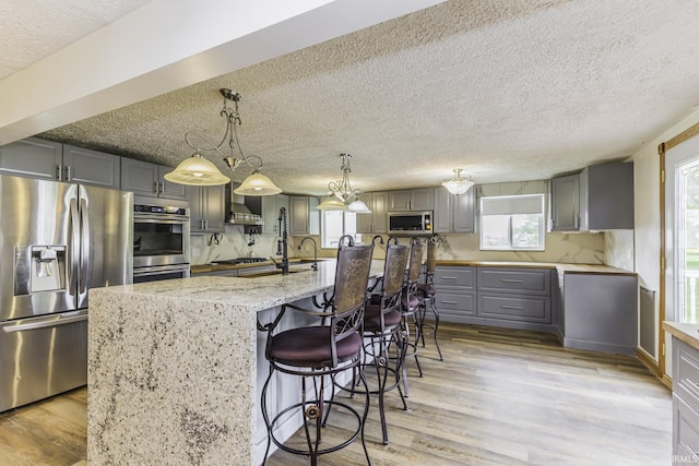 11009 S County Road 300 W, Muncie, IN 47302 - kitchen featuring appliances with stainless steel finishes, gray cabinetry, light wood-type flooring, a textured ceiling, and light stone counters
