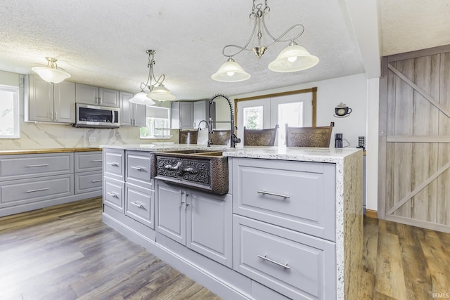 11009 S County Road 300 W, Muncie, IN 47302 - kitchen with gray cabinets, stainless steel microwave, wood finished floors, a textured ceiling, and pendant lighting
