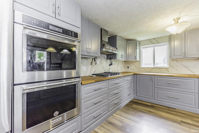 11009 S County Road 300 W, Muncie, IN 47302 - kitchen with gray cabinets, butcher block countertops, appliances with stainless steel finishes, wall chimney exhaust hood, and a textured ceiling