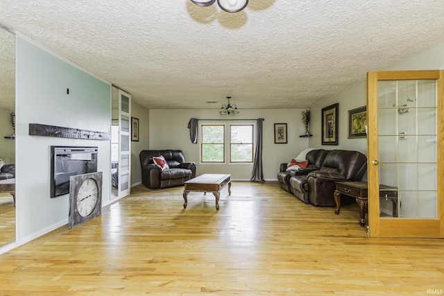 11009 S County Road 300 W, Muncie, IN 47302 - living area featuring light wood-style floors, a textured ceiling, a glass covered fireplace, and baseboards