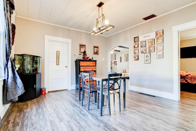 1409 Main St, Vincennes, IN 47591 - dining room featuring arched walkways, wood finished floors, crown molding, baseboards, and a chandelier