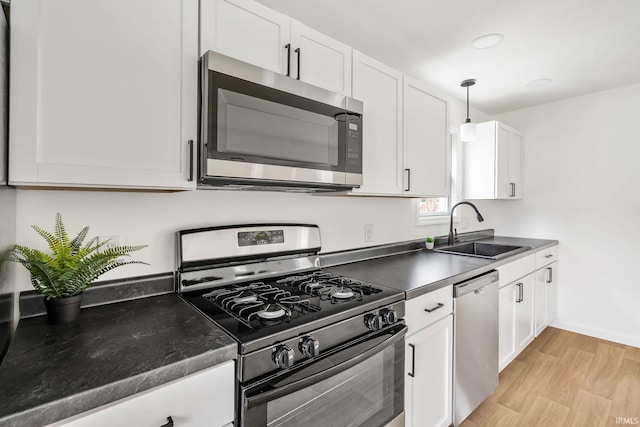516 W Pike St, Warsaw, IN 46580 - kitchen with stainless steel appliances, a sink, light wood-style floors, white cabinetry, and dark countertops