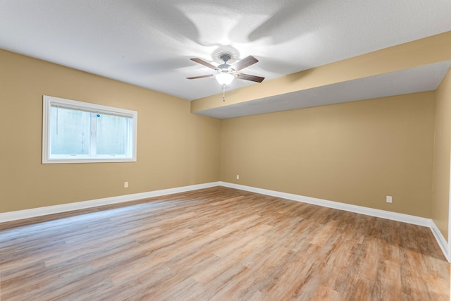 spare room featuring a ceiling fan, light wood finished floors, baseboards, and a textured ceiling