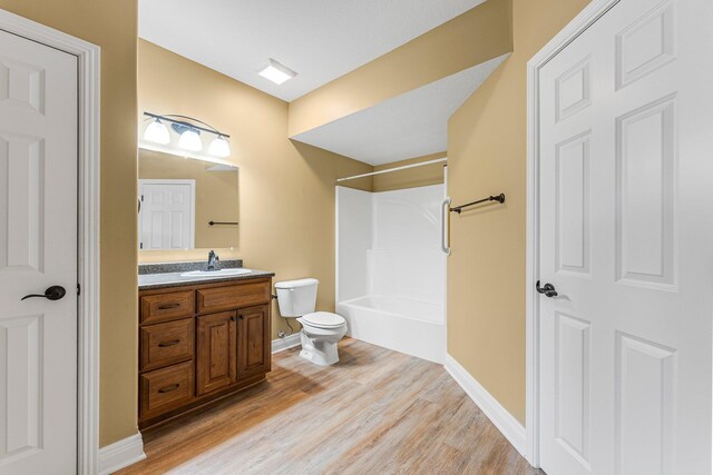 full bathroom featuring toilet, wood finished floors, vanity, baseboards, and bathing tub / shower combination