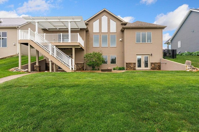 back of house featuring a wooden deck, stairway, a lawn, french doors, and stone siding