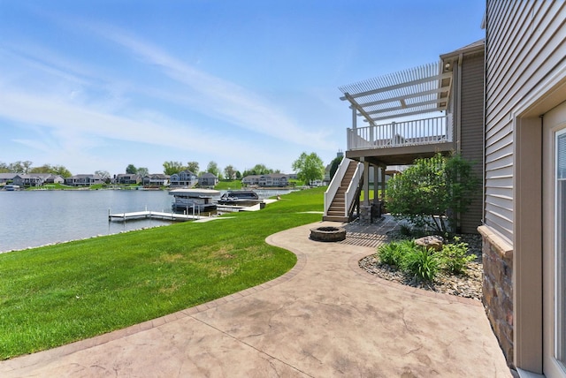view of grassy yard featuring stairway, a patio, an outdoor fire pit, a water view, and a boat dock
