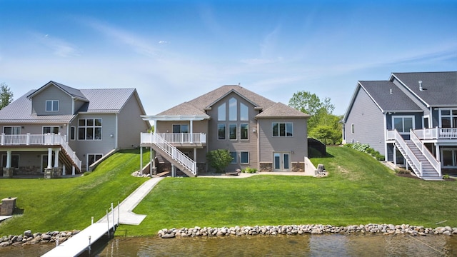 rear view of property with stairs, a deck with water view, a yard, and a patio