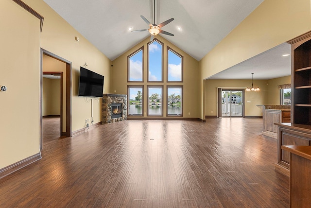 unfurnished living room featuring a fireplace, a ceiling fan, a chandelier, wood finished floors, and high vaulted ceiling