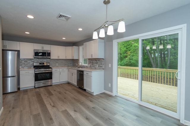 3214 Burr Oak Ave, Elkhart, IN 46517 - kitchen featuring stainless steel appliances, a sink, white cabinets, tasteful backsplash, and light wood-style floors