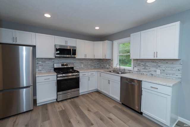 3214 Burr Oak Ave, Elkhart, IN 46517 - kitchen with appliances with stainless steel finishes, a sink, white cabinetry, backsplash, and wood finished floors