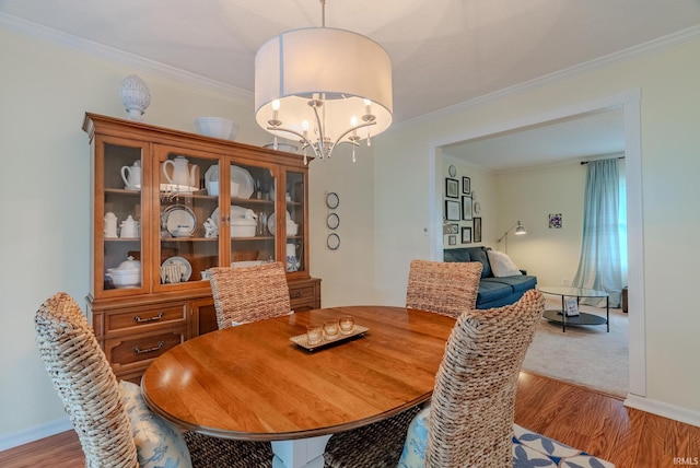 dining area featuring ornamental molding, light wood-style floors, a chandelier, and baseboards