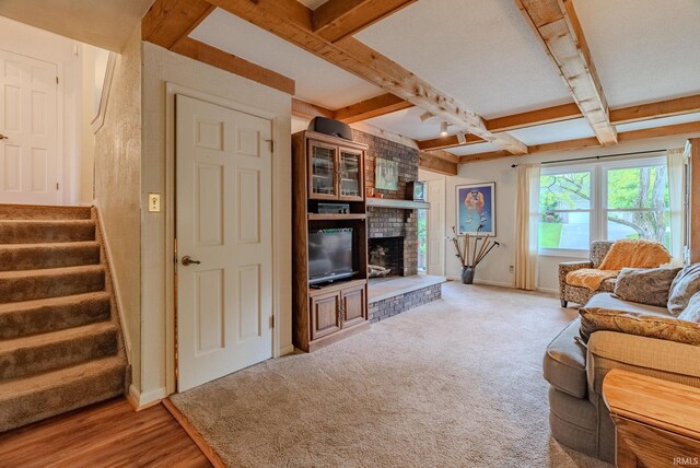 living room featuring a fireplace, beam ceiling, stairs, baseboards, and carpet floors
