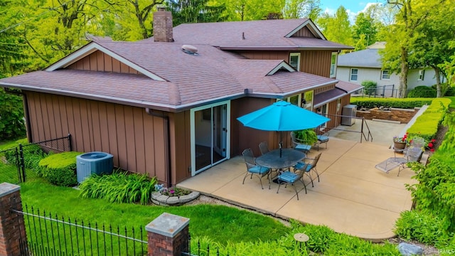 rear view of property with a chimney, board and batten siding, central air condition unit, roof with shingles, and a patio area