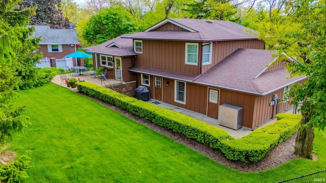 rear view of property with board and batten siding, a patio area, roof with shingles, and view of scattered trees