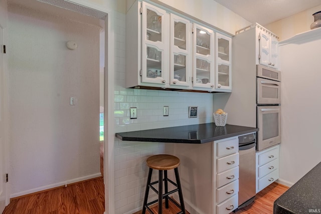 kitchen featuring light wood-style flooring, dark countertops, and white cabinetry