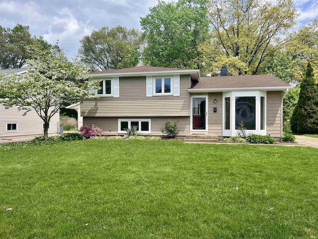 split level home with a front yard and a shingled roof