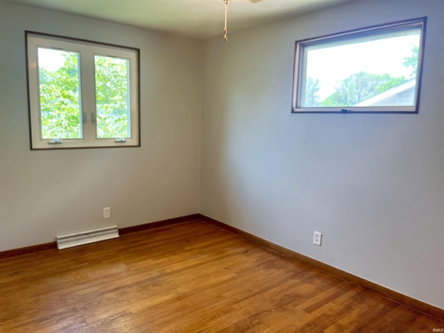 empty room featuring healthy amount of natural light, light wood-type flooring, and baseboards