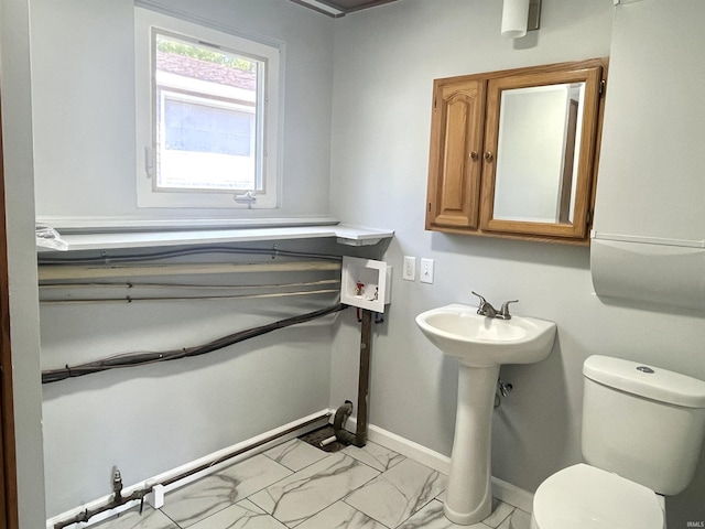 bathroom with marble look tiles, toilet, and baseboards