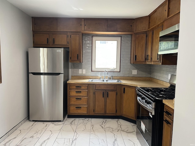 kitchen with appliances with stainless steel finishes, a sink, light countertops, and light marble finish flooring