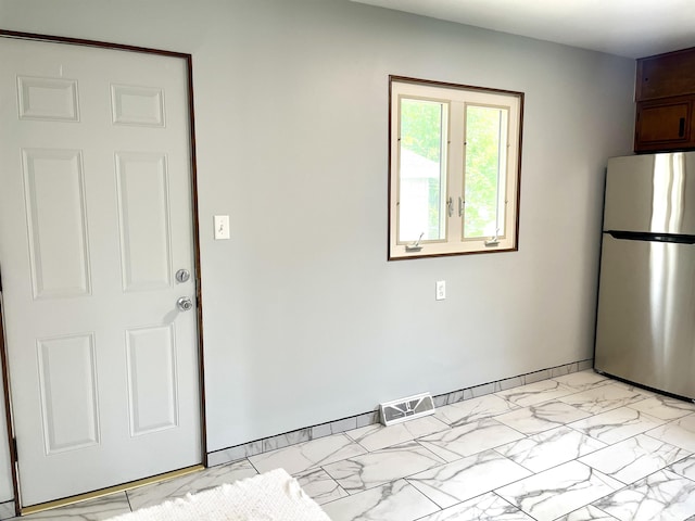 kitchen featuring freestanding refrigerator and light marble finish flooring