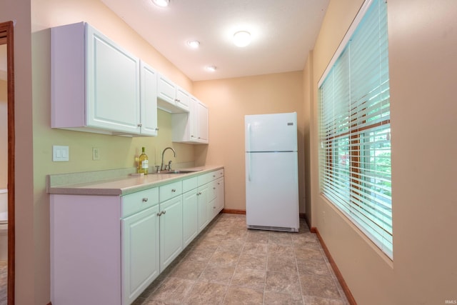 6015 E State Road 46, Bloomington, IN 47401 - kitchen featuring freestanding refrigerator, a sink, light countertops, baseboards, and white cabinetry