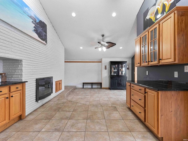 4038 Fahlsing Rd, Woodburn, IN 46797 - kitchen with vaulted ceiling, ceiling fan, a fireplace, glass insert cabinets, and light tile patterned flooring