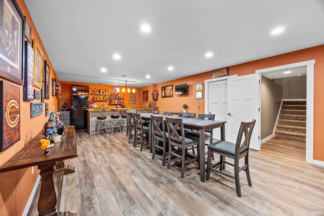 dining room featuring stairs, recessed lighting, light wood-type flooring, baseboards, and bar area