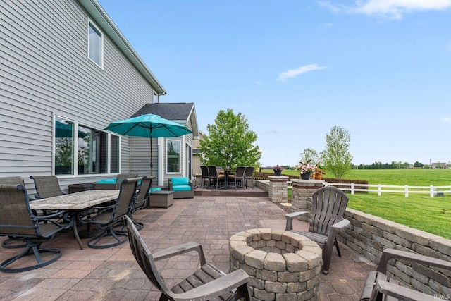 view of patio / terrace with outdoor dining area, an outdoor fire pit, and a rural view