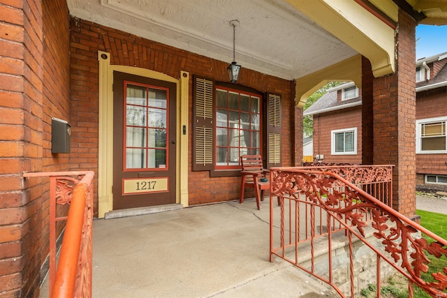 property entrance featuring a porch and brick siding