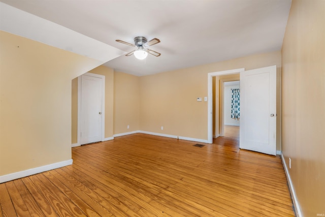 spare room featuring ceiling fan, light wood-type flooring, and baseboards