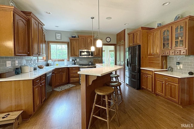 kitchen with stainless steel appliances, dark wood-style flooring, a sink, tasteful backsplash, and recessed lighting