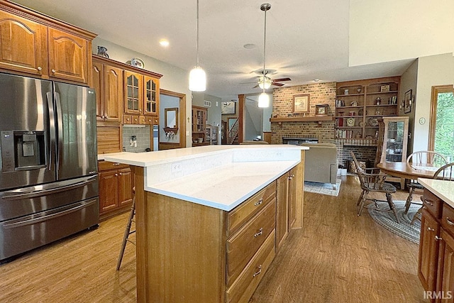 kitchen featuring stainless steel fridge, a fireplace, a center island, wood finished floors, and recessed lighting