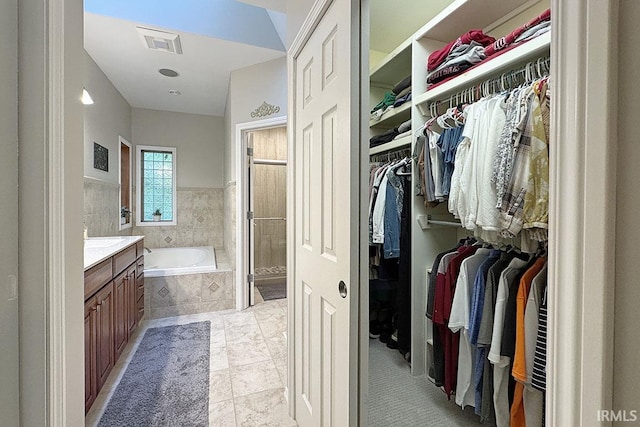 bathroom featuring a garden tub, a shower stall, a spacious closet, and vanity