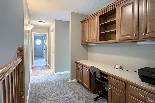 office featuring built in desk, light colored carpet, and baseboards