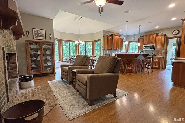 living area with a ceiling fan, a chandelier, light wood-style flooring, recessed lighting, and a fireplace