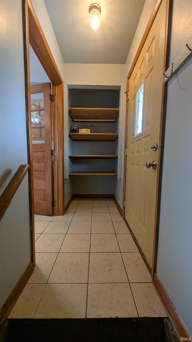 hallway with light tile patterned flooring, built in features, and baseboards
