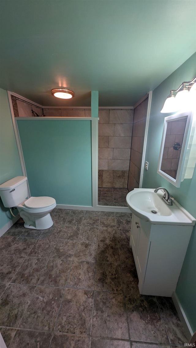 bathroom with toilet, vanity, baseboards, and a shower