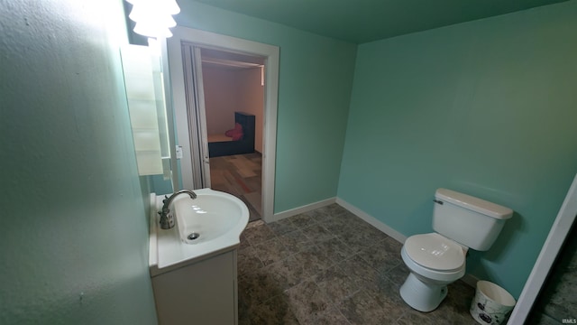 half bathroom with vanity, toilet, and baseboards