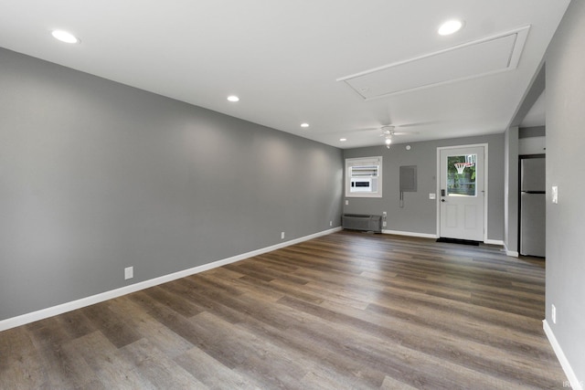 unfurnished room with attic access, wood finished floors, recessed lighting, baseboards, and an AC wall unit